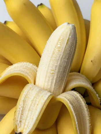 Friske bananer hele og i skiver, i skål og på rustikt bord