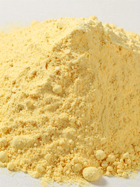 Gult majsmel i pulverform i en keramikskål på træbord