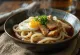 Stamina udon serveret i skål med udon-nudler, stegt kyllingekød, æg og sojasauce-baseret sauce