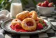 Zeppole fyldt med jordbærsyltetøj, drysset med flormelis, serveret på et rustikt fad