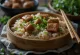 Braiseret svinekød zongzi pakket i bambusblade, serveret med friske forårsløg