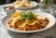 Chilaquiles con frijoles refritos – tortilla med rød sauce, bønner, ost og Creme Fraiche